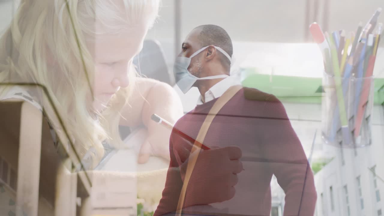 Composite video of african american man wearing face mask against caucasian girl studying at school