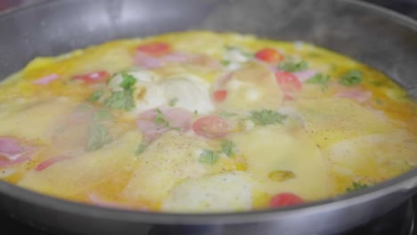 omelet with cheese and vegetables baking in a skillet