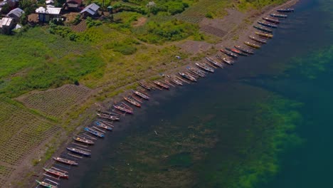 drone view of fishing boats docked on shore of lake mainit, philippines