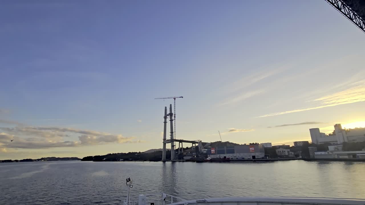Wide angle shot from sea showing old Sotra Bridge and new bridge tower under construction in evening light