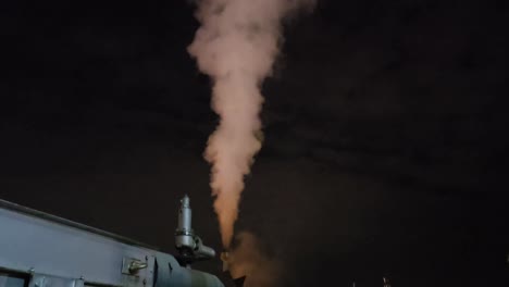 steam rising from industrial pipe at night