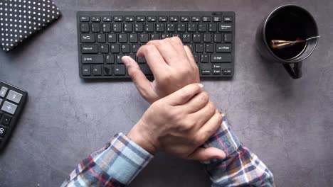 person typing on a keyboard, with a calculator and tea cup