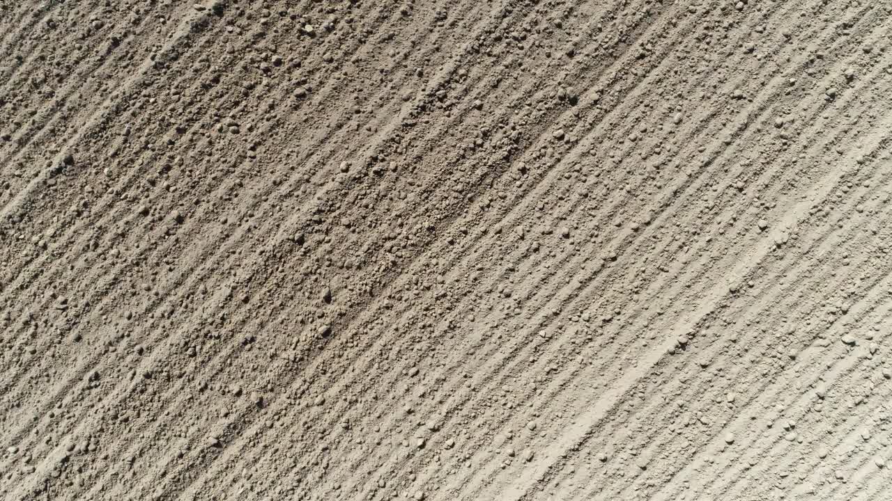 Drone shot turning and zooming out over a ploughed field