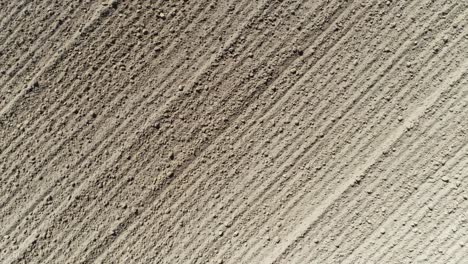 drone shot turning and zooming out over a ploughed field