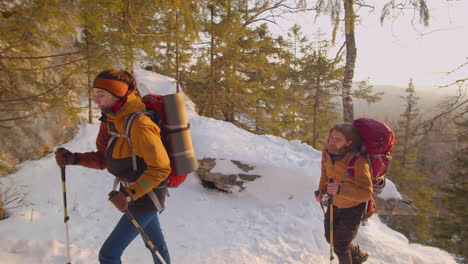 couple going uphill with trekking poles on winter day