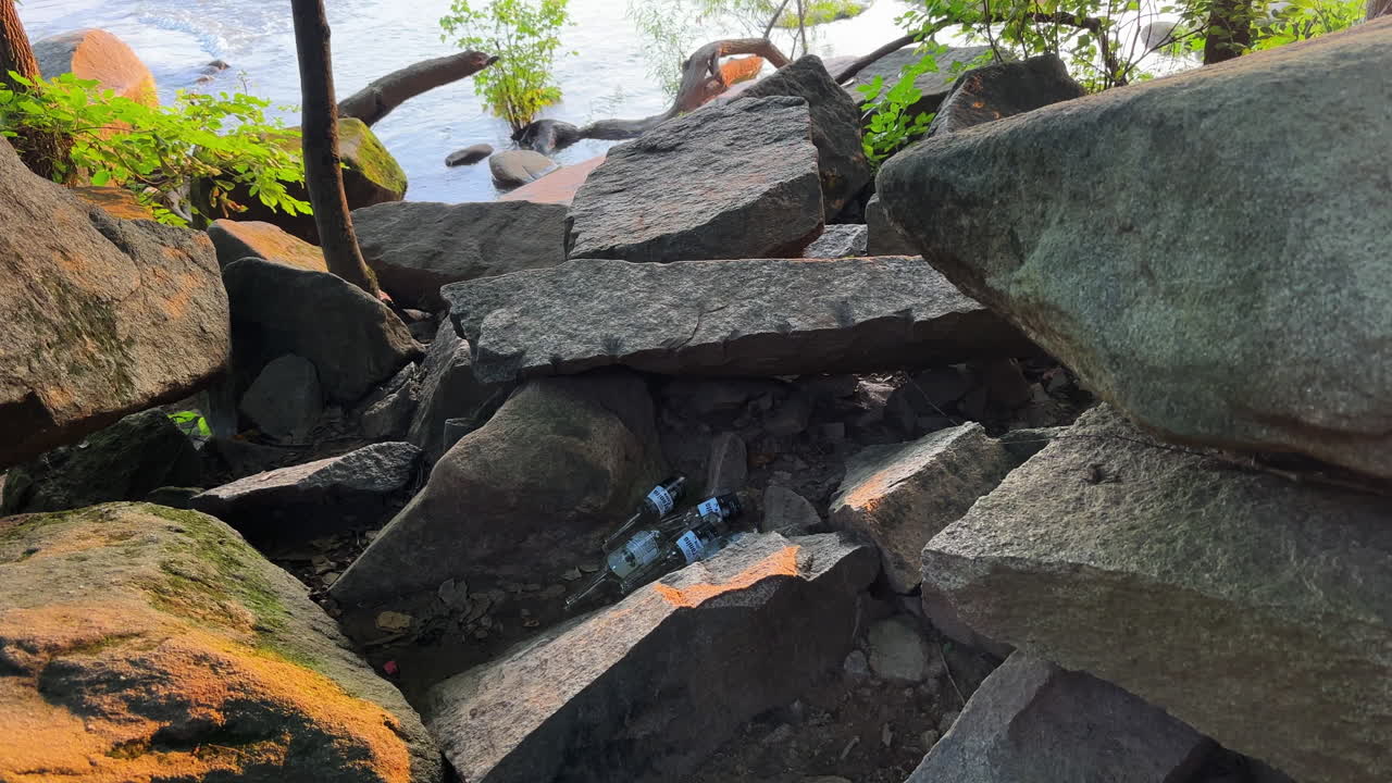 A pile of beer bottles nestled in the rocks at Pony Pasture, James River in Richmond Virginia