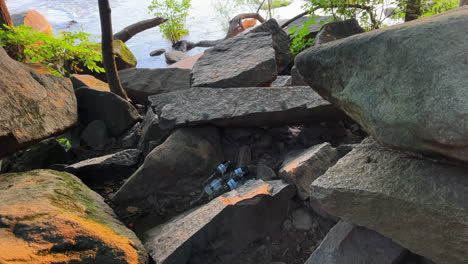 a pile of beer bottles nestled in the rocks at pony pasture, james river in richmond virginia