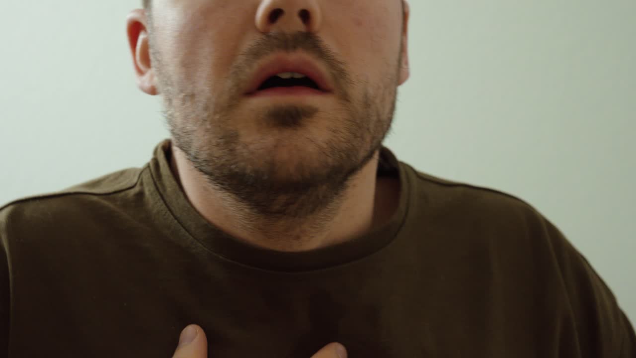 Primo piano di un uomo che fatica a respirare con difficoltà respiratorie visibili. Concetto di problemi respiratori, sintomi di asma, respiro affannoso ed emergenza sanitaria.