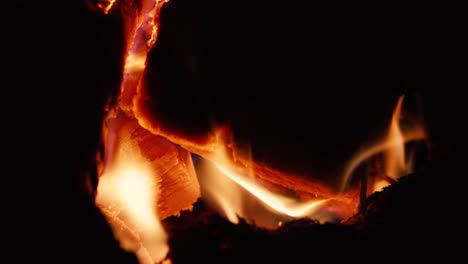 details with wood and embers burning in a camp fire pit at night.