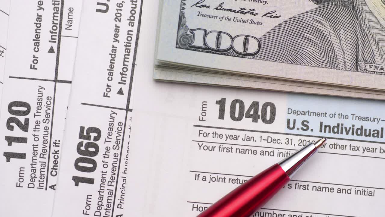 formularios de impuestos con dinero y bolígrafo.