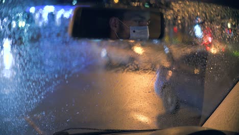 the man sits in the car and takes off the medical mask