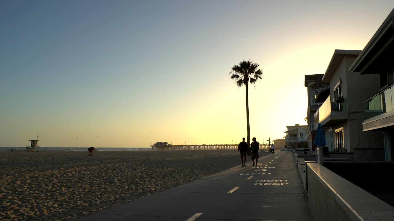 Persone che camminano a Newport Beach al tramonto