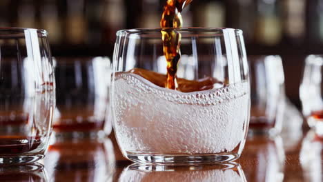 pouring whiskey into glasses at a bar