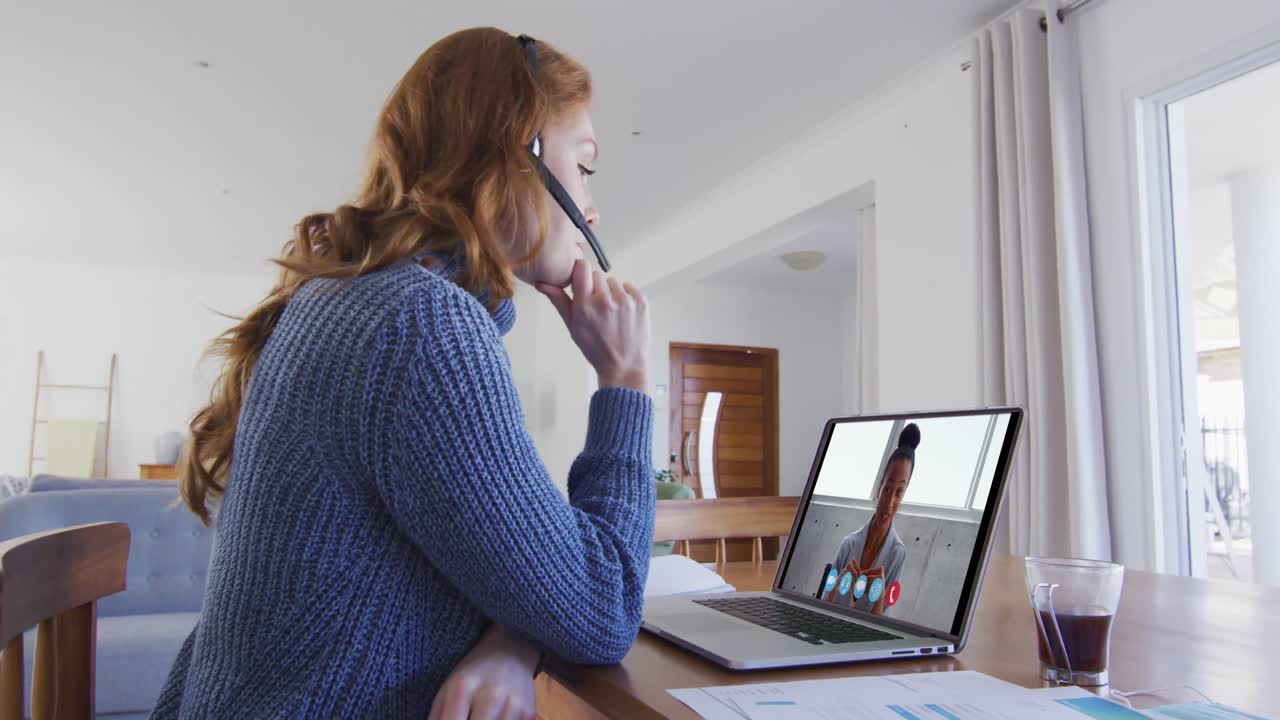 Caucasian woman using laptop and phone headset on video call with female colleague