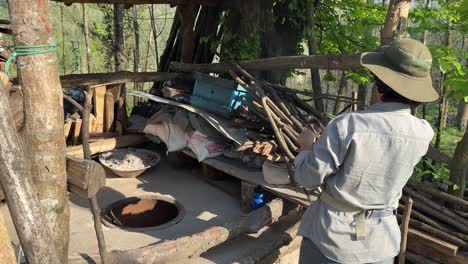 A-young-woman-put-dry-wooden-stick-into-the-clay-old-traditional-oven-in-rural-village-area-in-mountain-forest-in-nature-prepare-to-make-Turkish-flat-bread-kneading-dough