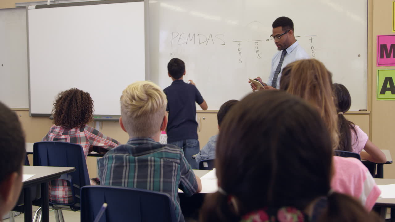 niño de escuela escribiendo en la pizarra en la clase delantera, filmado en r3d