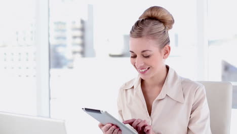 una mujer de negocios rubia feliz usando una tableta.