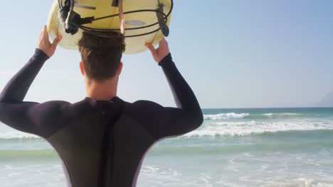 male surfer carrying surfboard on his head at beach 4k