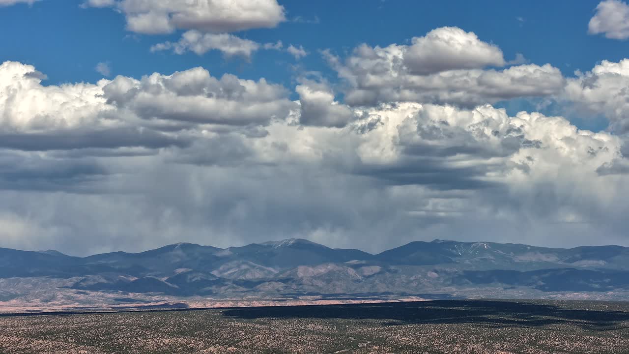 Un drammatico hyperlapse con drone cattura il rapido movimento delle nuvole temporalesche sopra la cima del Monte Baldy. Il cielo turbolento e il paesaggio montano aspro creano una transizione e uno sfondo naturali epici.