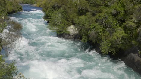 A-slow-mothion-pan-and-tilt-shot-of-the-top-of-the-Huka-Falls,-a-water-fall-in-Taupo,-New-Zealand