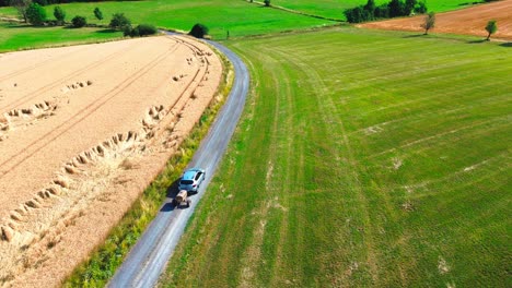 aerial-drone-shot-over-ripe-wheatfield-and-lush-green-pasture,-4k