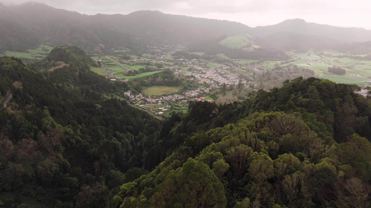 Colinas arborizadas e a vila do vale das Furnas em São Miguel, Açores, vista aérea.
