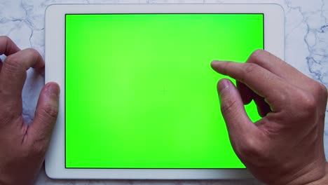 man hands using tablet with green screen chroma key on marble table