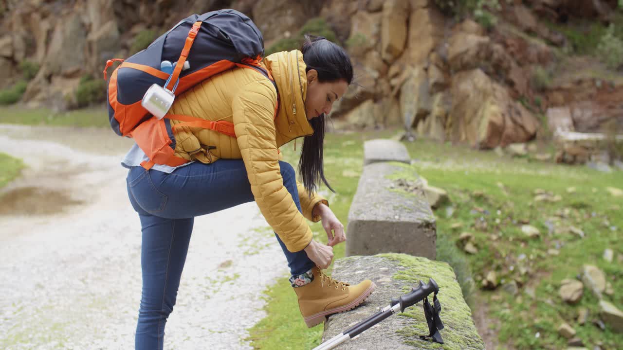 una mujer excursionista atando sus cordones