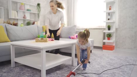 Cute-little-girl-helping-her-mother-at-home-vacuuming-the-house.