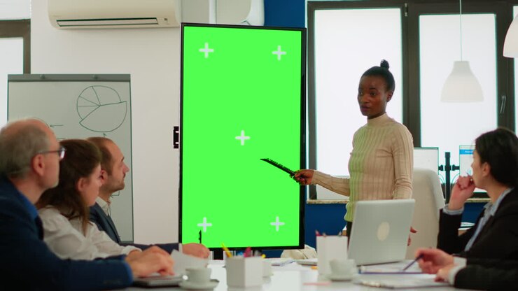 Diverse woman standing in start up office discussing strategy with green screen display