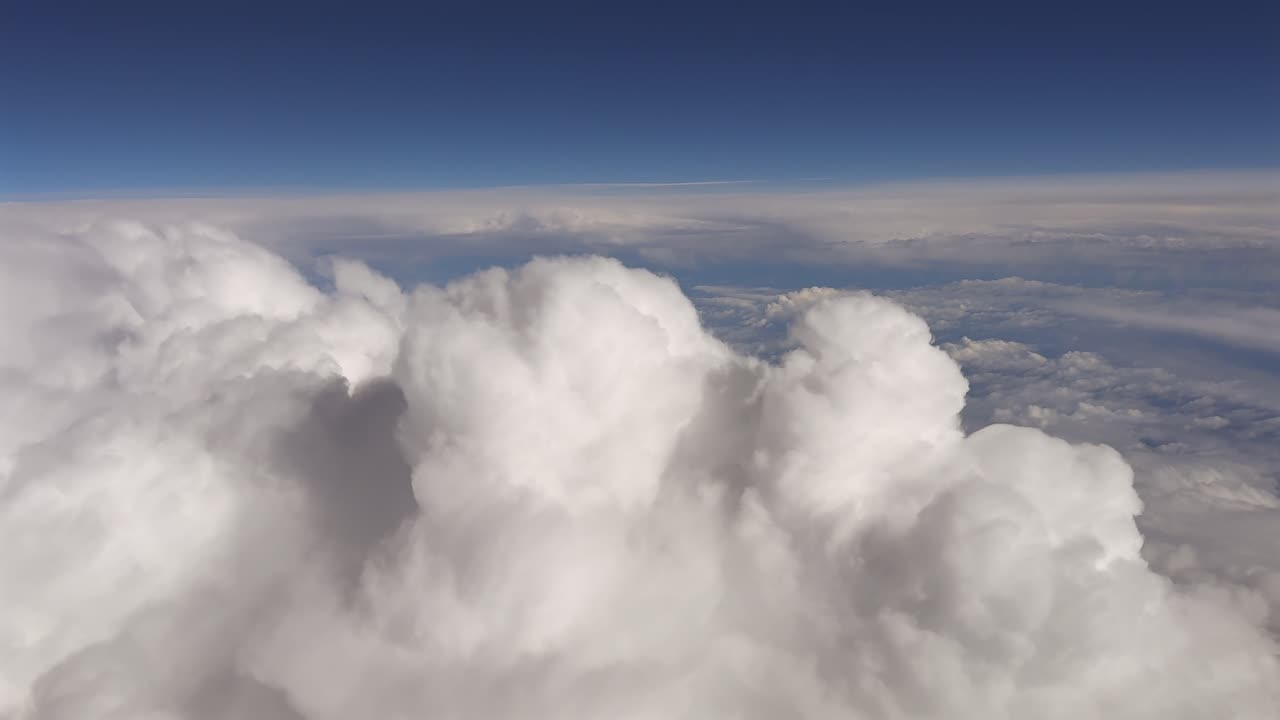 Vista della cabina di pilotaggio di un jet che vola ad alta quota sopra nuvole cumuliformi e tempestose simili al cotone
