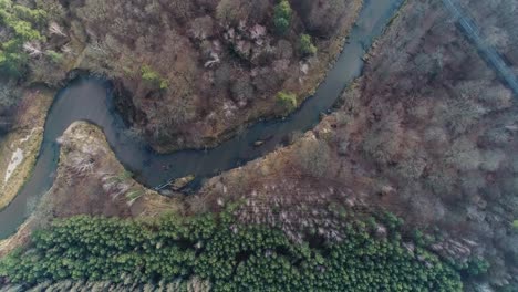 bridge over winding mala panew river surrounded by forest, spinning overhead aerial
