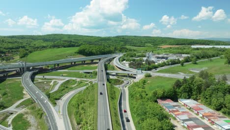 an aerial drone moves forward above an intricate tangle of a highway junction, showcasing cars navigating complex roundabouts and intersecting roads