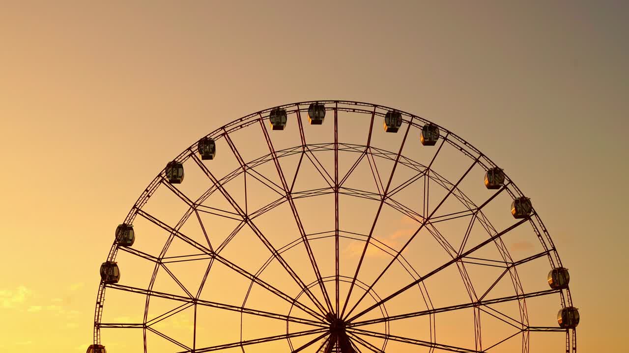 Ferris wheel against a sunset sky.