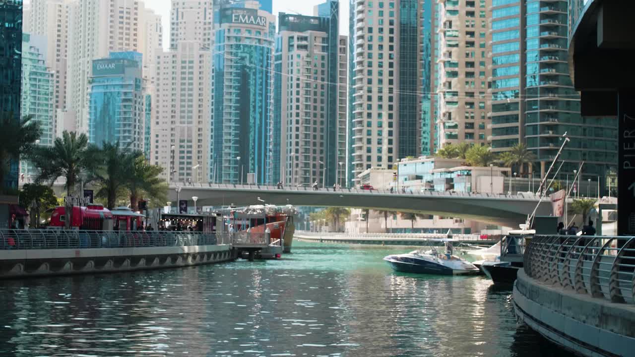Pont sur le canal d'eau au port de Dubaï Marina avec mouettes et tours.