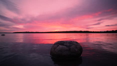 Großer-Stein-Im-Wasser-Bei-Farbenprächtigem-Sonnenuntergang-Am-See