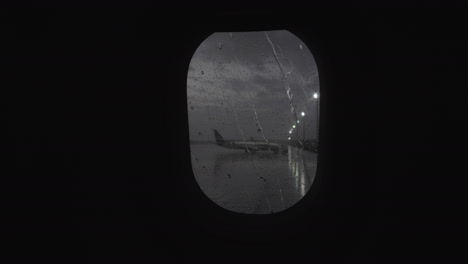 Iluminador-Con-Rayas-De-Lluvia-Vista-Al-Aeropuerto-Desde-Un-Avión-En-Movimiento