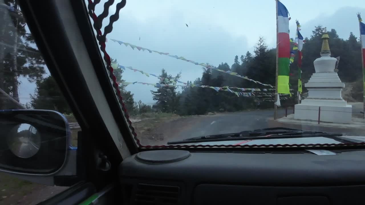 POV jeep ride through Nepal's rugged interior. Driving to the left of buddhist hinduist prayer flags