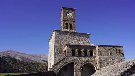 Filmische-Aufnahme-Des-Uhrturms-Mit-Stein--Und-Gewölbten-Mauern-Der-Burg-Argjiro-Im-Blauen-Hellen-Himmelshintergrund