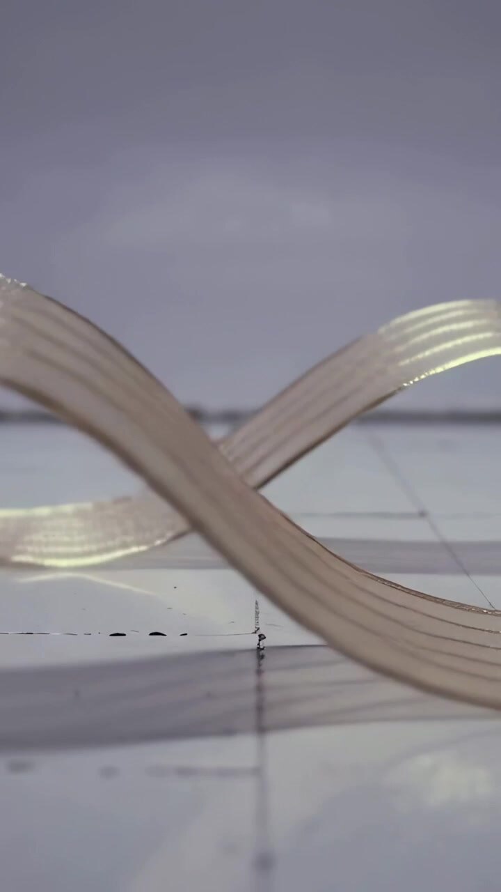 Vertical video: Starting arc rising, two glossy striped ribbons crossing into S waves on tiled seam
