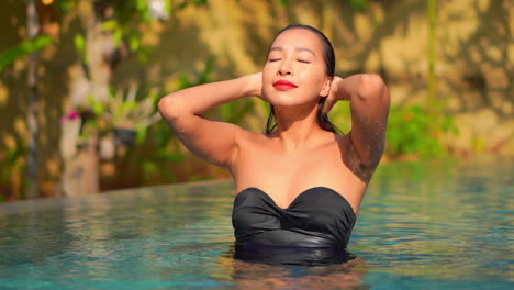 El-Primer-Plano-De-Una-Mujer-Bonita-Que-Emerge-De-La-Piscina-Se-Desliza-Hacia-Atrás-El-Cabello-Mojado-Y-Luego-Sonríe-A-La-Cámara