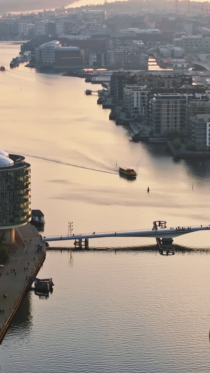 Aerial drone view of people moving on the Quay Bridge across the port of Copenhagen, Denmark in the evening. Vertical