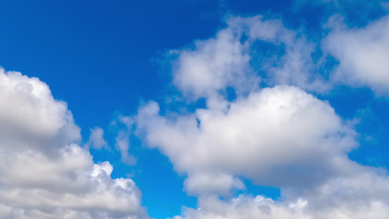 Beautiful azure sky in summer with white clouds. Cumulus cloudscape formation. Low angle view. Timelapse.