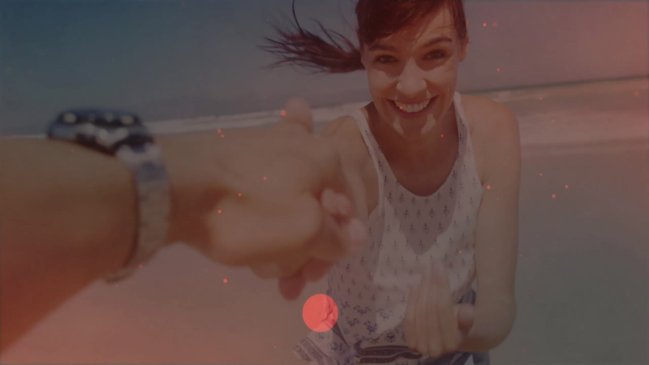 Holding hands at beach, woman smiling and enjoying animation of waves