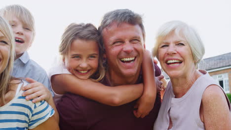 Three-generation-family-smiling-to-camera-in-the-garden