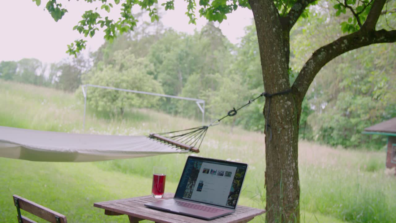 Homeoffice setting with laptop on table in garden next to hammock