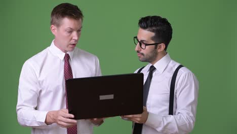 two young multi-ethnic businessmen working together against green background