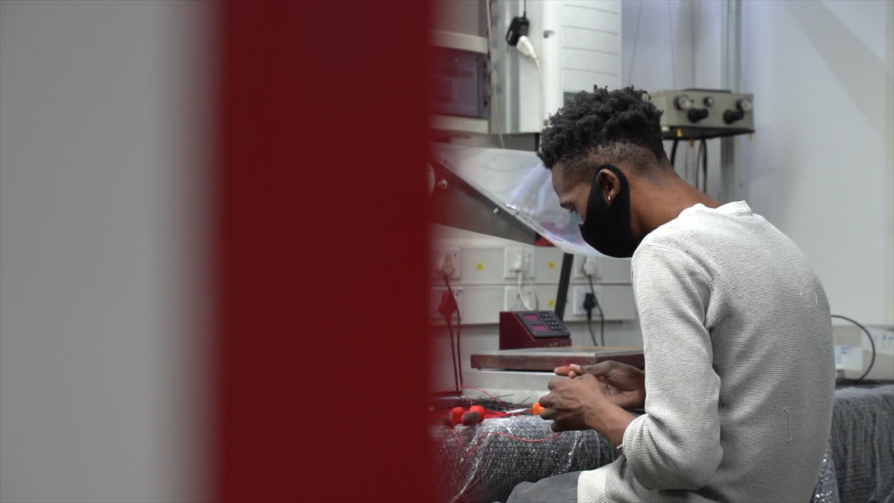 Male worker sitting at table in workshop working with wires.