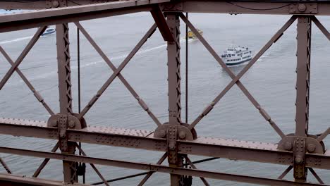 looking at passenger ferry water taxi boats though a bridge on hudson river, new york city nyc