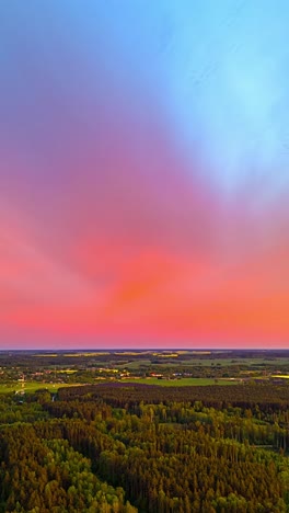 a breathtaking sunset paints the sky with vibrant pink and blue hues over vast green forests and distant fields in latvia